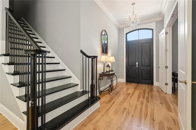 entrance foyer featuring stairway, an inviting chandelier, wood finished floors, ornamental molding, and baseboards
