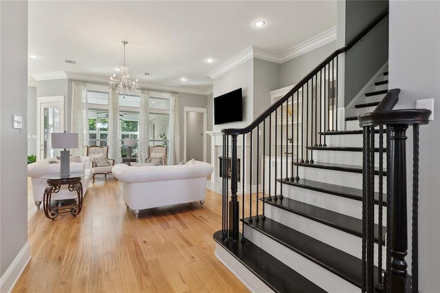 living room with a chandelier, light wood-style floors, stairs, and crown molding