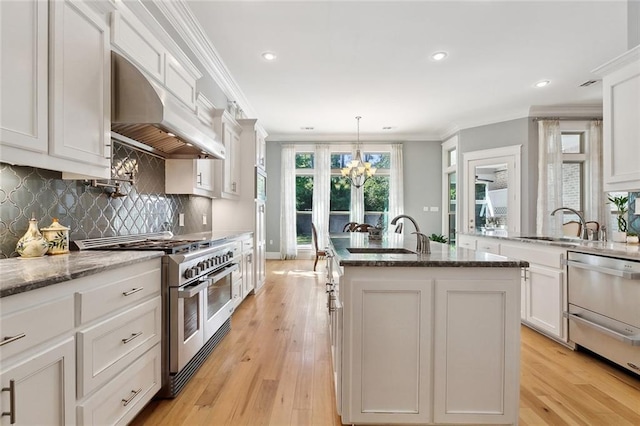 kitchen featuring ventilation hood, a sink, an inviting chandelier, range with two ovens, and crown molding