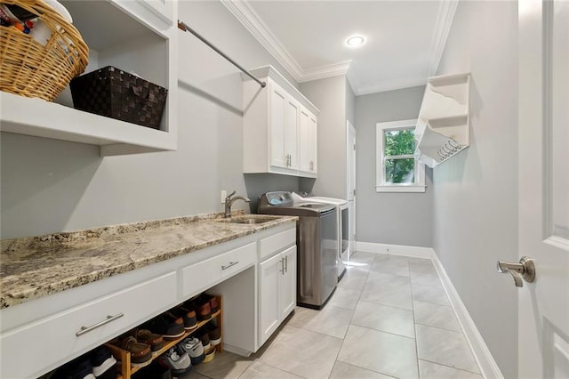 laundry area featuring a sink, baseboards, cabinet space, washer and dryer, and ornamental molding