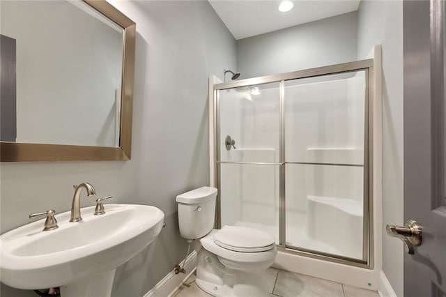 bathroom with toilet, baseboards, a sink, and a stall shower