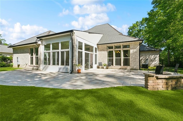 back of property featuring a lawn, a patio area, a sunroom, and brick siding
