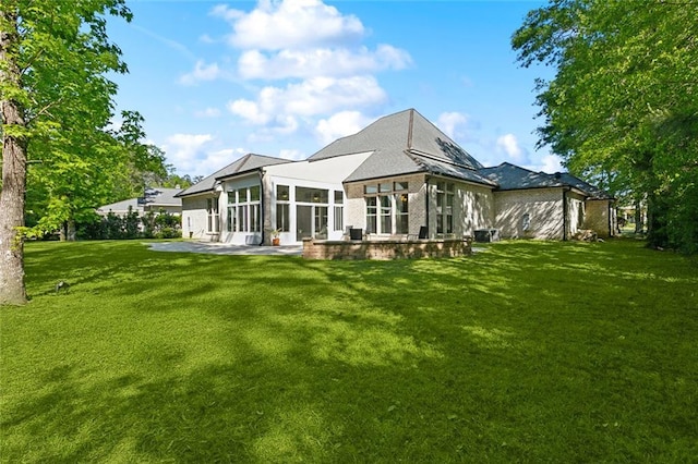 rear view of house with a lawn, a sunroom, and a patio