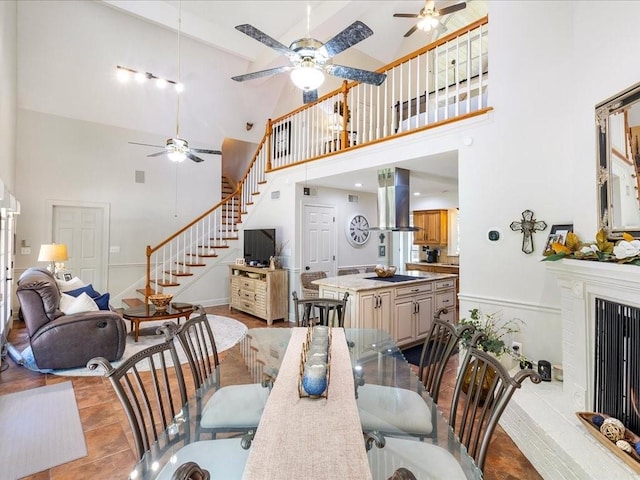 31035 Horseshoe Island Rd, Lacombe, LA 70445 - dining area with high vaulted ceiling, ceiling fan, stairs, and a fireplace with raised hearth