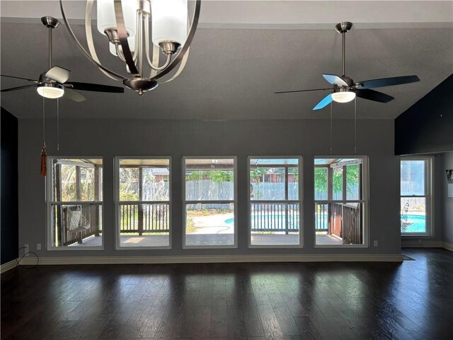 interior space with ceiling fan with notable chandelier, baseboards, lofted ceiling, and dark wood finished floors