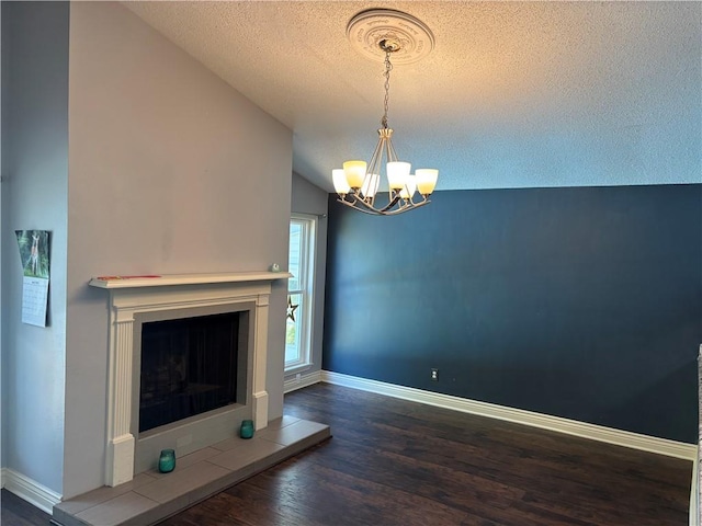 unfurnished living room featuring a textured ceiling, a chandelier, lofted ceiling, wood finished floors, and a fireplace