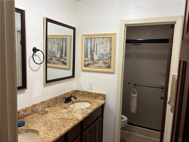 bathroom featuring tile patterned flooring, double vanity, toilet, and a sink