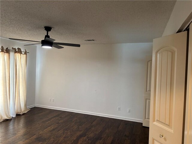 unfurnished room with a textured ceiling, dark wood-style flooring, baseboards, visible vents, and a ceiling fan