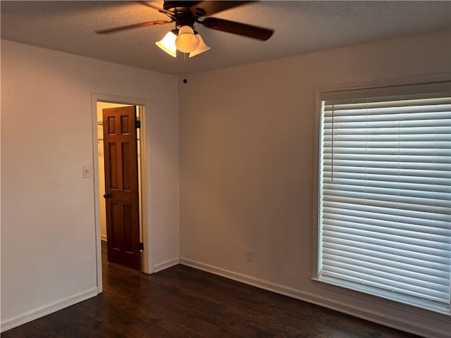 empty room featuring a ceiling fan, baseboards, a textured ceiling, and dark wood-type flooring