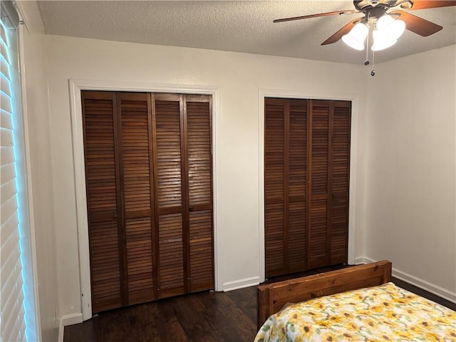 bedroom featuring wood finished floors, multiple closets, a ceiling fan, and baseboards