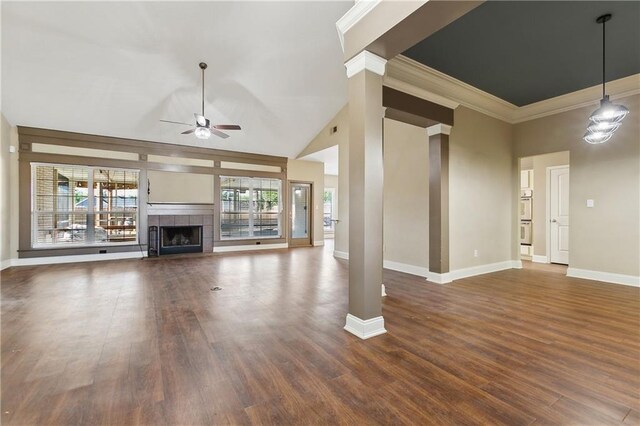 unfurnished living room with crown molding, ceiling fan, a tiled fireplace, baseboards, and dark wood-type flooring