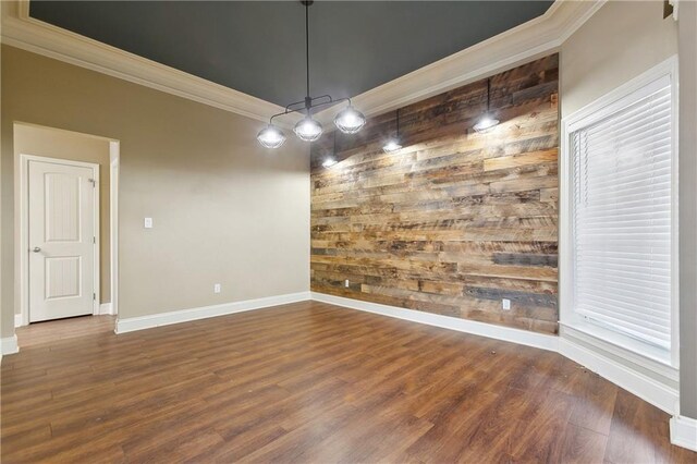 unfurnished dining area featuring baseboards, wood finished floors, wood walls, and ornamental molding