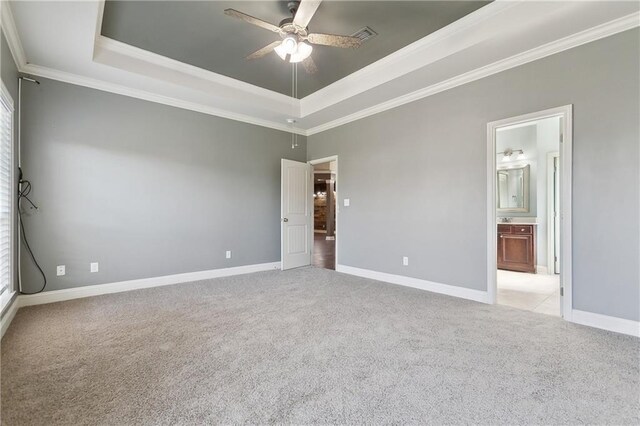 unfurnished bedroom with baseboards, light carpet, crown molding, and a raised ceiling