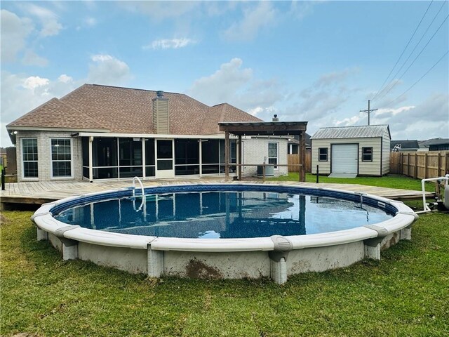 rear view of house with a fenced in pool, fence, a yard, an outdoor structure, and a sunroom