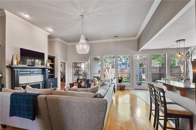 2436 Cours Carson St, Mandeville, LA 70448 - living room featuring light wood-style flooring, a chandelier, a fireplace, and ornamental molding