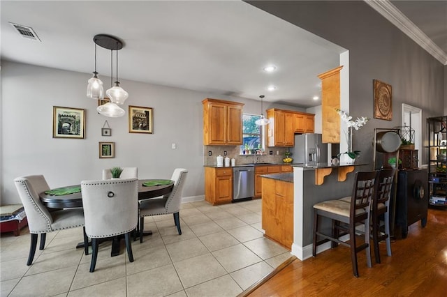 2436 Cours Carson St, Mandeville, LA 70448 - kitchen featuring appliances with stainless steel finishes, a peninsula, hanging light fixtures, a kitchen bar, and dark countertops