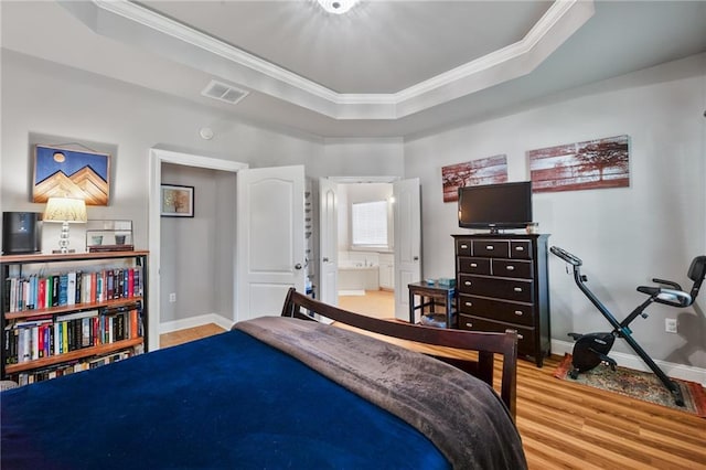 2436 Cours Carson St, Mandeville, LA 70448 - bedroom featuring light wood-type flooring, a raised ceiling, crown molding, baseboards, and connected bathroom