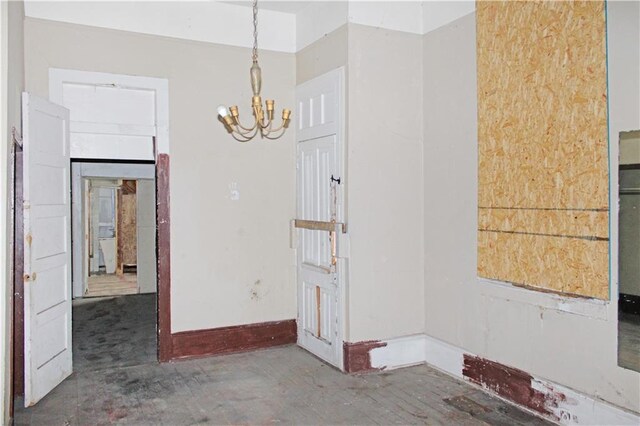 unfurnished room featuring baseboards, a notable chandelier, and unfinished concrete flooring