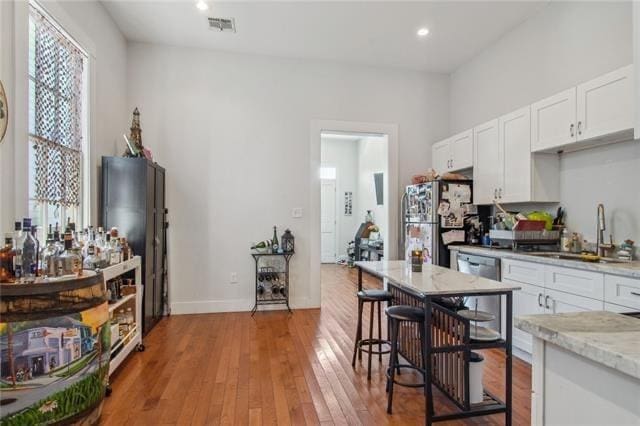 264545 Saint Ann St, New Orleans, LA 70119 - kitchen with stainless steel appliances, visible vents, a sink, light wood-style floors, and white cabinetry