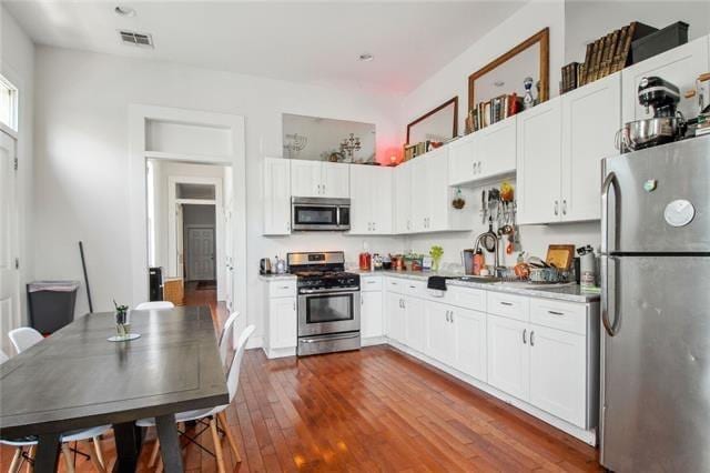 264545 Saint Ann St, New Orleans, LA 70119 - kitchen featuring white cabinets, appliances with stainless steel finishes, dark wood-style floors, and visible vents