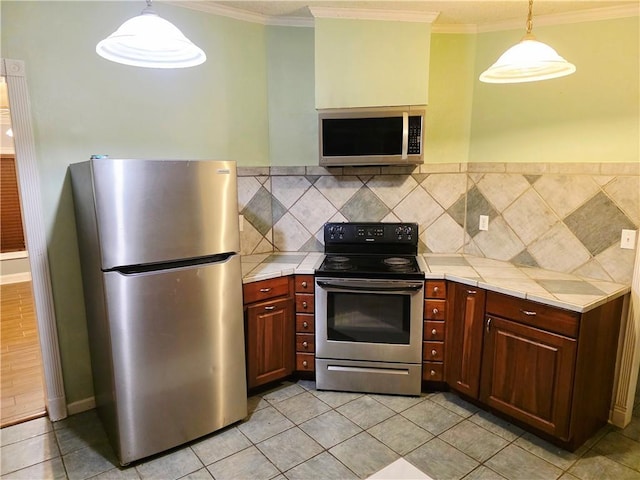 4967A Jean Lafitte Blvd, Lafitte, LA 70067 - kitchen featuring stainless steel appliances, tile counters, light tile patterned flooring, and crown molding