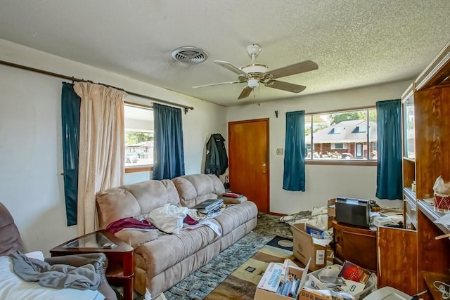 living area featuring ceiling fan, wood finished floors, a textured ceiling, and visible vents