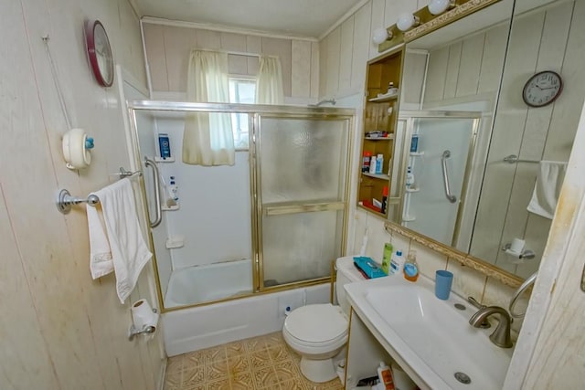 bathroom with toilet, bath / shower combo with glass door, and a sink