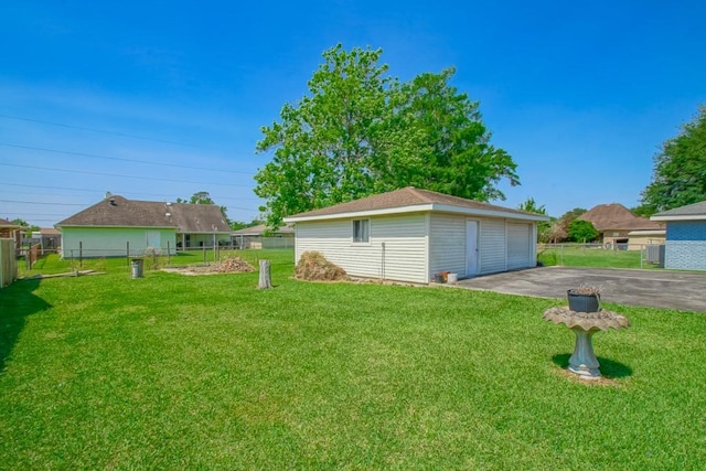 view of yard with fence, an outdoor structure, and a detached garage
