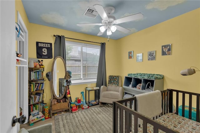 bedroom with a nursery area and ceiling fan