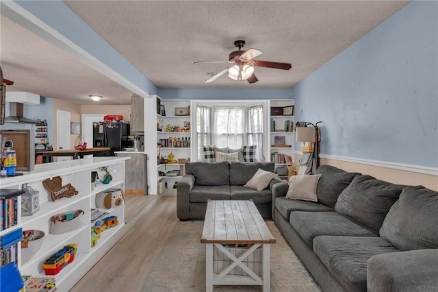 living area with a ceiling fan, a textured ceiling, and light wood-style floors