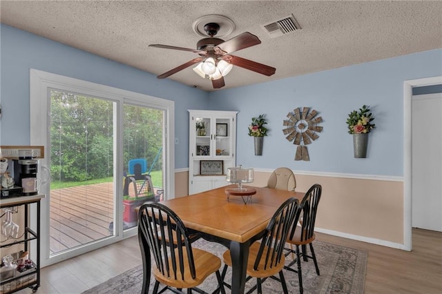 dining area with ceiling fan, light wood-type flooring, and a textured ceiling