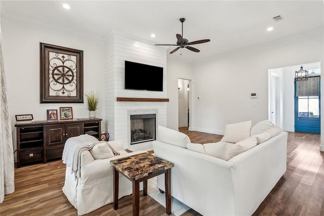 living area with visible vents, recessed lighting, ceiling fan with notable chandelier, dark wood-type flooring, and ornamental molding