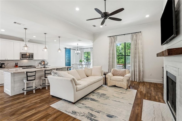 living room with ceiling fan with notable chandelier, visible vents, and recessed lighting