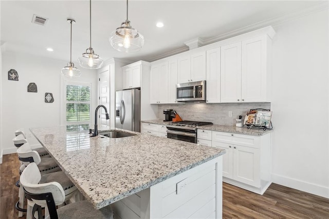 kitchen featuring stainless steel appliances, a sink, a center island with sink, baseboards, and visible vents