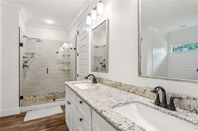 full bathroom with crown molding, wood finished floors, a sink, and a stall shower