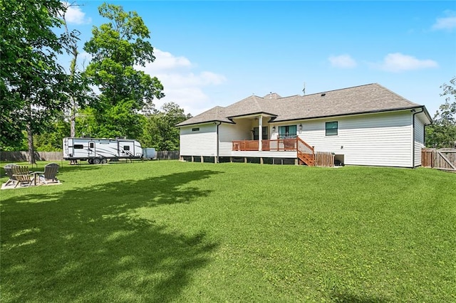 back of property featuring a fenced backyard, a wooden deck, a fire pit, and a lawn