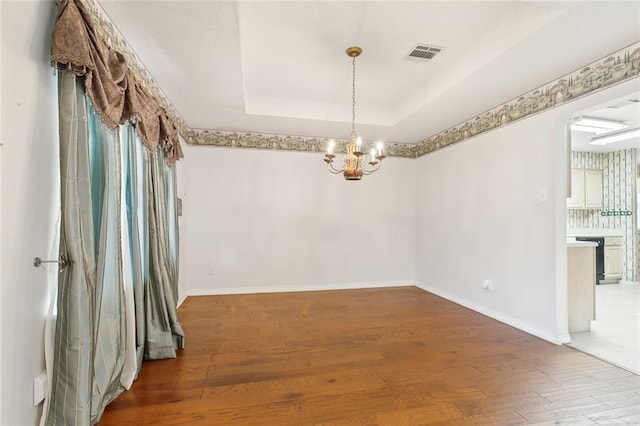 205 Newman Ave, Jefferson, LA 70121 - empty room featuring wood finished floors, an inviting chandelier, a tray ceiling, baseboards, and visible vents