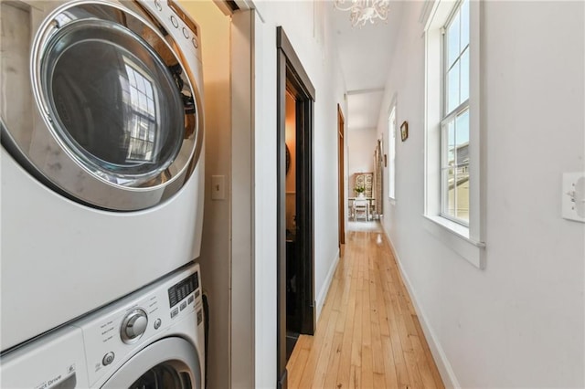 2426 Chippewa St, New Orleans, LA 70130 - clothes washing area featuring estacked washer and dryer, light wood-style flooring, baseboards, and a chandelier