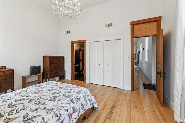 2426 Chippewa St, New Orleans, LA 70130 - bedroom featuring light wood-style floors, a chandelier, a closet, a towering ceiling, and baseboards