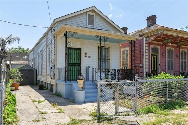 2426 Chippewa St, New Orleans, LA 70130 - shotgun-style home with covered porch, a shed, fence, and an outbuilding