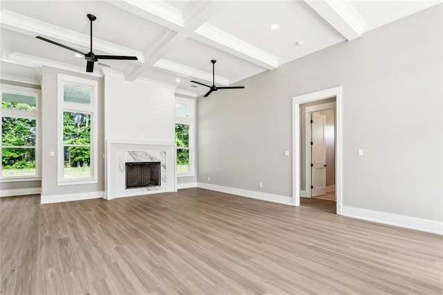 unfurnished living room with ceiling fan, beam ceiling, and light wood-type flooring
