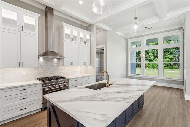 kitchen featuring a sink, coffered ceiling, decorative backsplash, wall chimney range hood, and stainless steel range