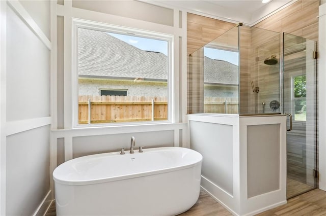 bathroom featuring a shower stall, a soaking tub, and wood finished floors