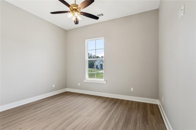 empty room with wood finished floors, visible vents, baseboards, and ceiling fan