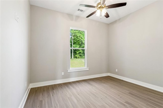 spare room with wood finished floors, visible vents, baseboards, and ceiling fan