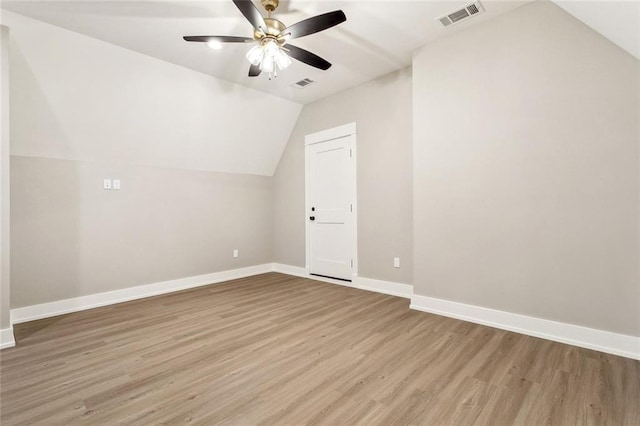 additional living space featuring vaulted ceiling, baseboards, visible vents, light wood-style floors, and a ceiling fan