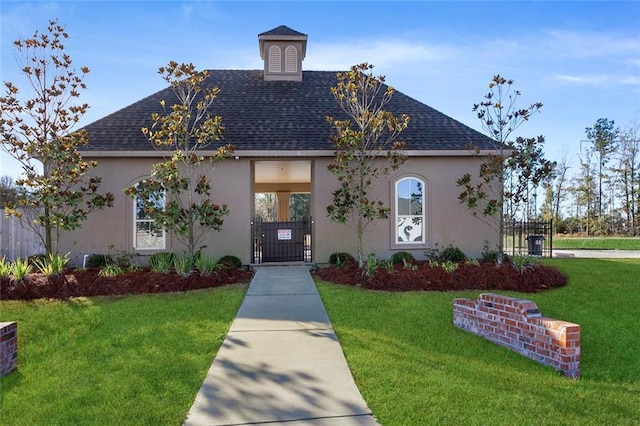 view of front facade featuring a gate, roof with shingles, a front lawn, and stucco siding