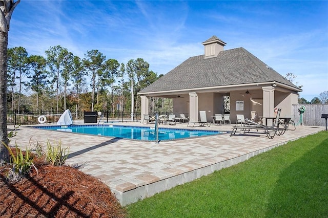 community pool with fence, a patio area, and ceiling fan