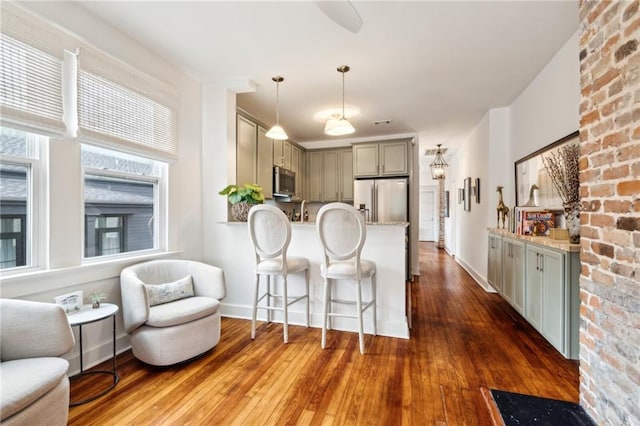 370507 Laurel St, New Orleans, LA 70115 - kitchen featuring decorative light fixtures, a peninsula, appliances with stainless steel finishes, hardwood / wood-style flooring, and a breakfast bar area
