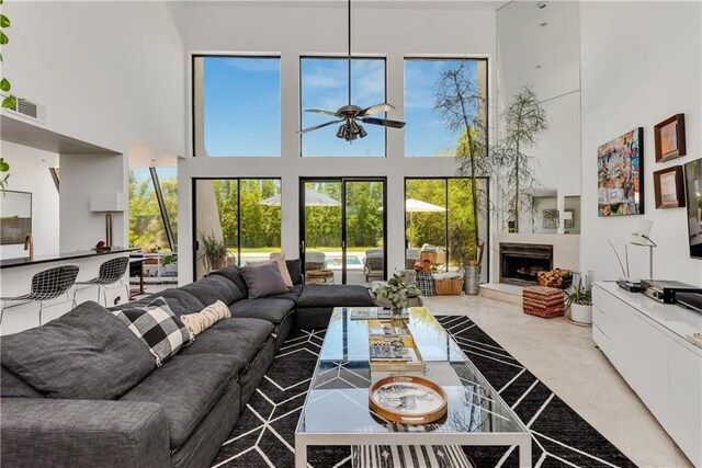 4809 Neyrey Dr, Metairie, LA 70002 - living room featuring a towering ceiling, a fireplace with raised hearth, a ceiling fan, and healthy amount of natural light